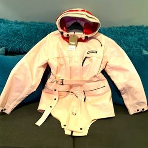 A pale pink BURBERRY RAINCOAT with belt. Hood has red and grey stripes.